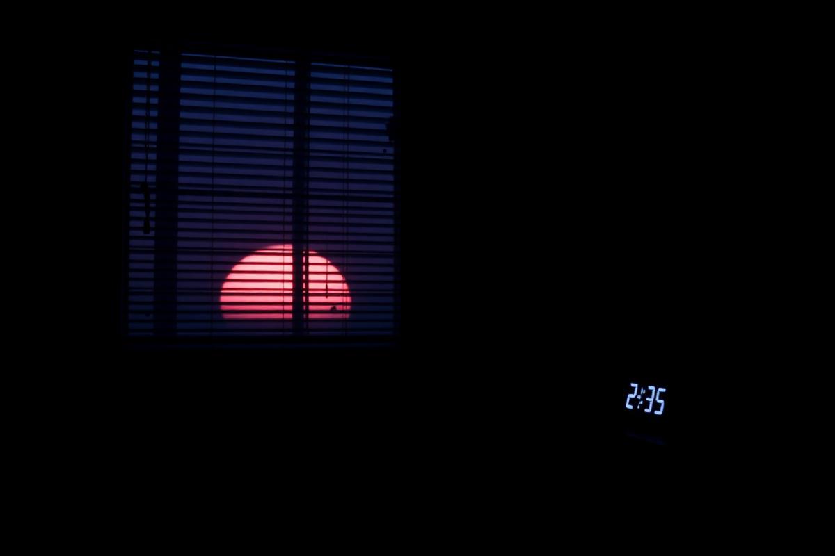 Smart alarm clock glowing beside a bed at dawn